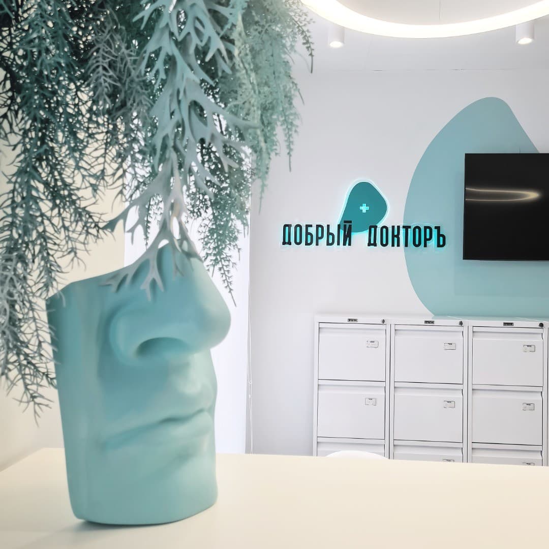 The Dobry Doktor sign at the clinic's reception, a teal face sculpture in front
